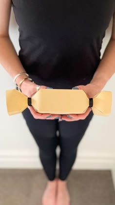 a person holding a skateboard in their hands and wearing black leggings, with one hand on the board