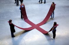 several people standing around a giant red ribbon