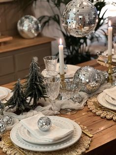 a dining room table set for christmas with plates and silverware, candles and decorations