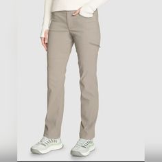 a woman in white sweater and khaki pants standing with her hands on her hips