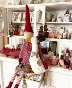 a stuffed bird sitting on top of a dresser next to a shelf filled with christmas decorations