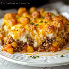 a white plate topped with lasagna covered in ground beef and cheese, on top of a wooden table