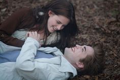 two people laying on the ground with one person touching his face and another looking at him