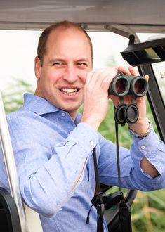 a man is looking through binoculars in the back of a truck while smiling at the camera