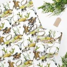 the wrapping paper is decorated with horses and cactuses on white background, surrounded by greenery