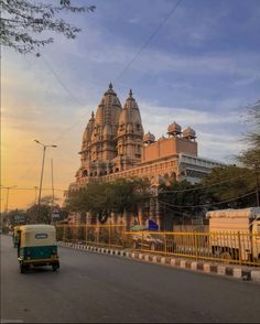 an old building is seen in the background as a car drives down the road near it