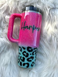 a pink and black leopard print coffee cup with the word happy painted on it's side