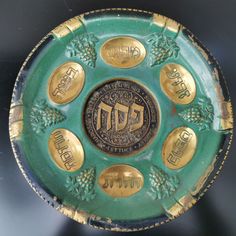 a green and gold plate with hebrew symbols on it