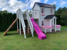 a pink slide next to a white house with flowers on the windows and door frames