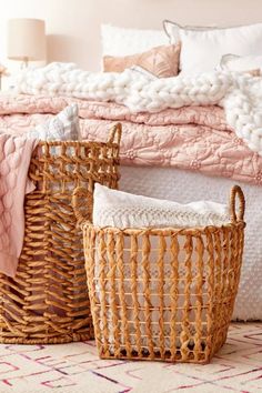 two baskets sitting on top of a bed next to a pink and white comforter