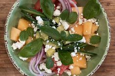 a green bowl filled with vegetables and cheese