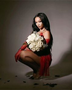 a woman kneeling down holding a bouquet of flowers