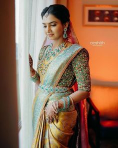 a woman standing in front of a window wearing a sari