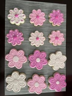 cookies decorated with pink and white icing are arranged on a baking sheet to look like flowers