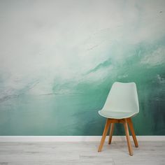 a white chair sitting in front of a wall with a green and blue painting on it