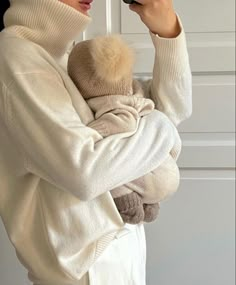 a woman holding a baby in her arms while taking a photo with a cell phone