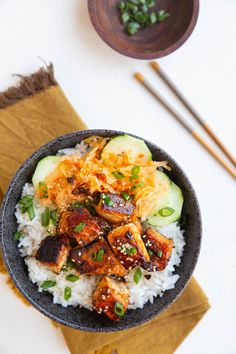 a bowl filled with rice, meat and veggies on top of a table