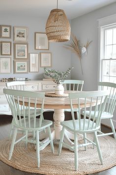 a dining room table with four chairs and pictures on the wall behind it, all in pastel green