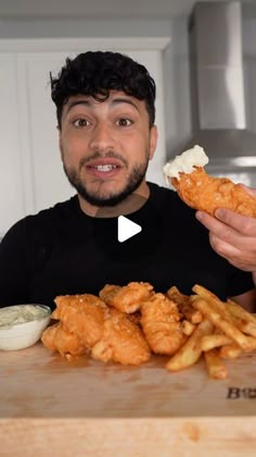 a man is holding up some fried food