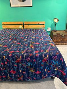 a bed with a blue bedspread and wooden headboard in a room that has green walls