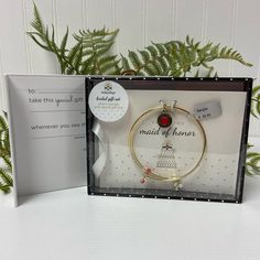 a gift set with a card, bracelet and brooch in a glass box on a table