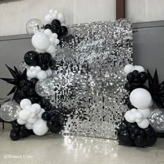 black and white balloons are arranged in front of a silver sequin backdrop with the words happy new year on it