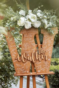 a wooden easel with writing on it and flowers in the top right hand corner