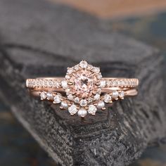 a pink diamond ring sitting on top of a rock