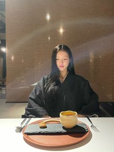 a woman sitting at a table in front of a bowl and plate with food on it