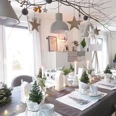 a dining room table set for christmas with white dishes and place settings on the table