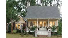 a small house with porches and plants on the front