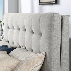 the headboard of a bed with pillows on it and a vase in the background