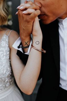 a man and woman holding each other's hands with tattoos on their wrists