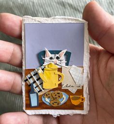 a person holding up a piece of paper with a cat on it