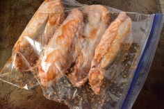 chicken wings wrapped in plastic sitting on top of a pan filled with seasoning and spices