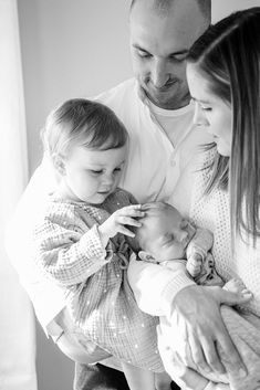 a black and white photo of a man holding a baby while two women hold him