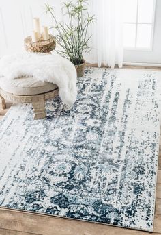 a blue and white area rug with an ornate design on the floor in front of a window