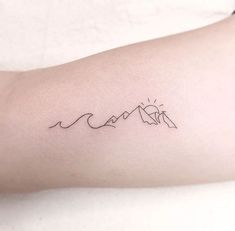 a woman's arm with a mountain and wave tattoo on the left inner arm