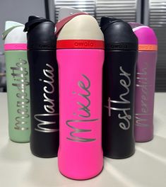 three different colored water bottles sitting next to each other on a white counter top in an office setting