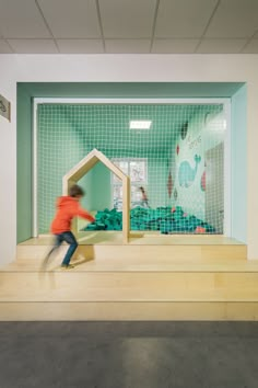 a child is playing in a play house made out of wood and plastic material with a green screen behind it