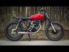 a red motorcycle parked next to a wooden fence