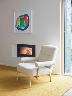 a white chair sitting in front of a fire place next to a painting on the wall