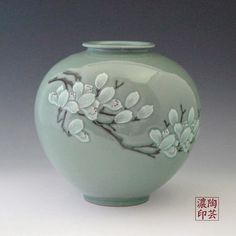 a green vase with flowers painted on it