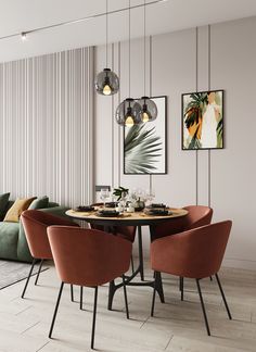 a dining table with four chairs around it in front of a green couch and two pictures on the wall