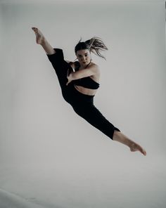 a woman in black shirt and leggings doing a dance move on white background