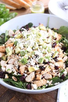 a salad with chicken, avocado and feta cheese in a white bowl