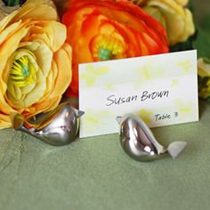 there is a place card holder with two birds on it next to flowers and leaves