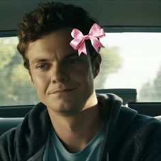 a man with a pink bow on his head in the back seat of a car