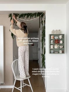 a woman hanging garland on the wall in her kitchen with instructions for how to hang it