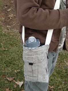 a young boy is holding a can in his back pocket while standing on the grass